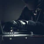 Masked Computer Hacker In Dark Room.